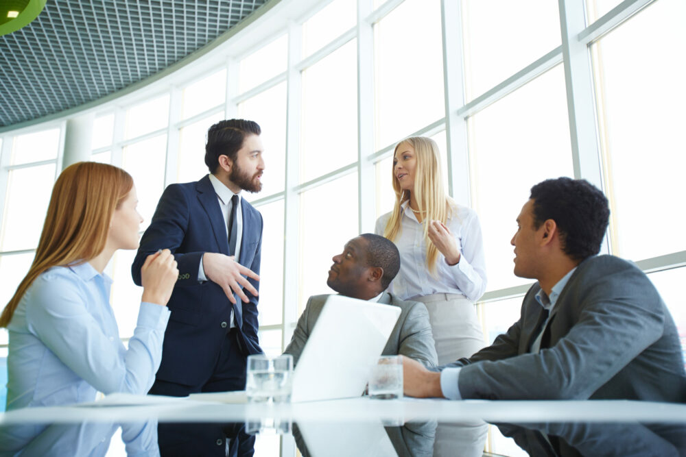 Group of business partners looking at their boss explaining his idea to employee